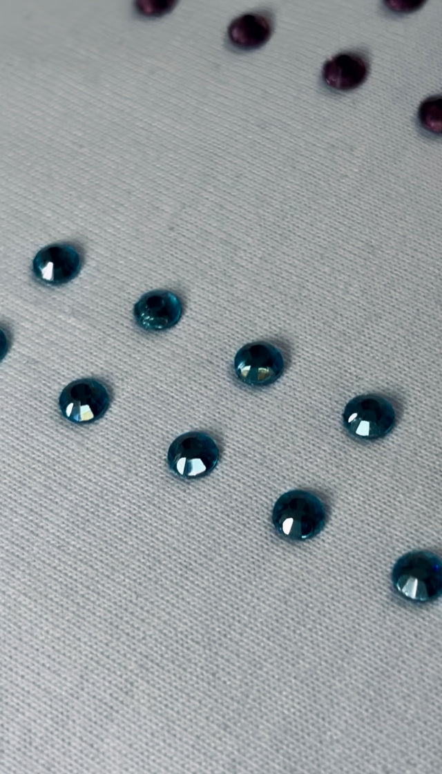 Close-up of teal rhinestones applied to textured fabric in a vertical pattern
