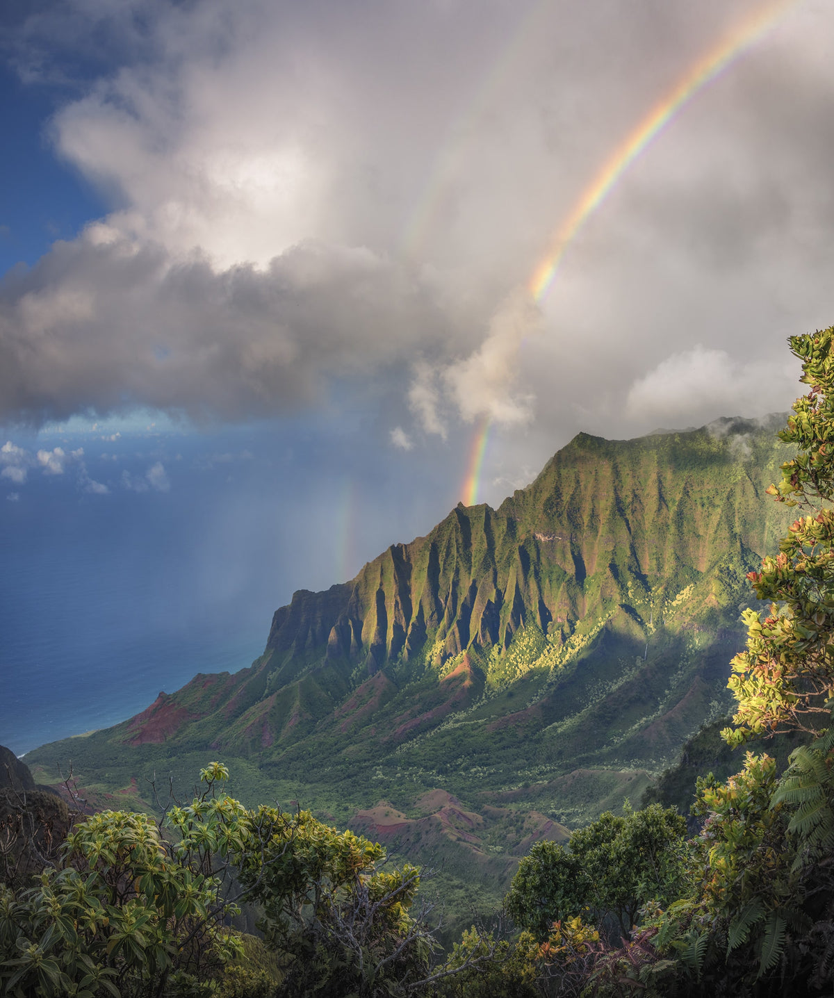 Dramatic mountain landscape with a natural rainbow emerging through clouds, symbol of light and spectrum