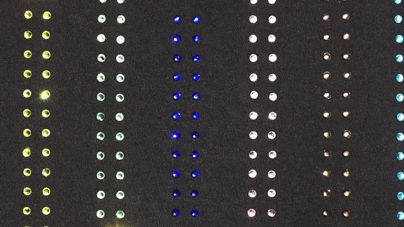 Close-up of vertical rainbow rhinestone stripes on a black Haus of MX Proud T-shirt.