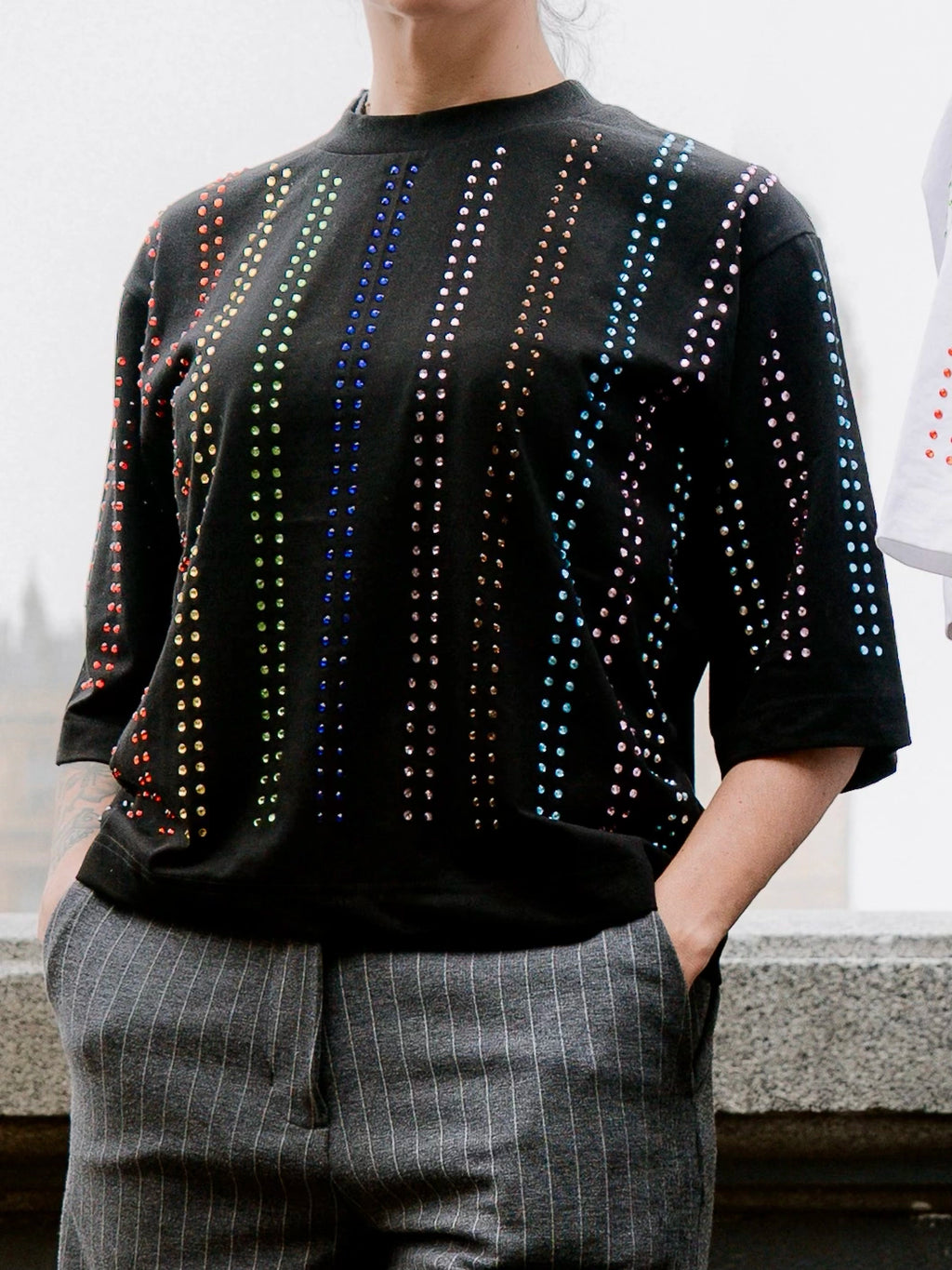 Close-up of black Proud T-shirt with vertical rainbow crystal lines, pride inspired, worn by a model