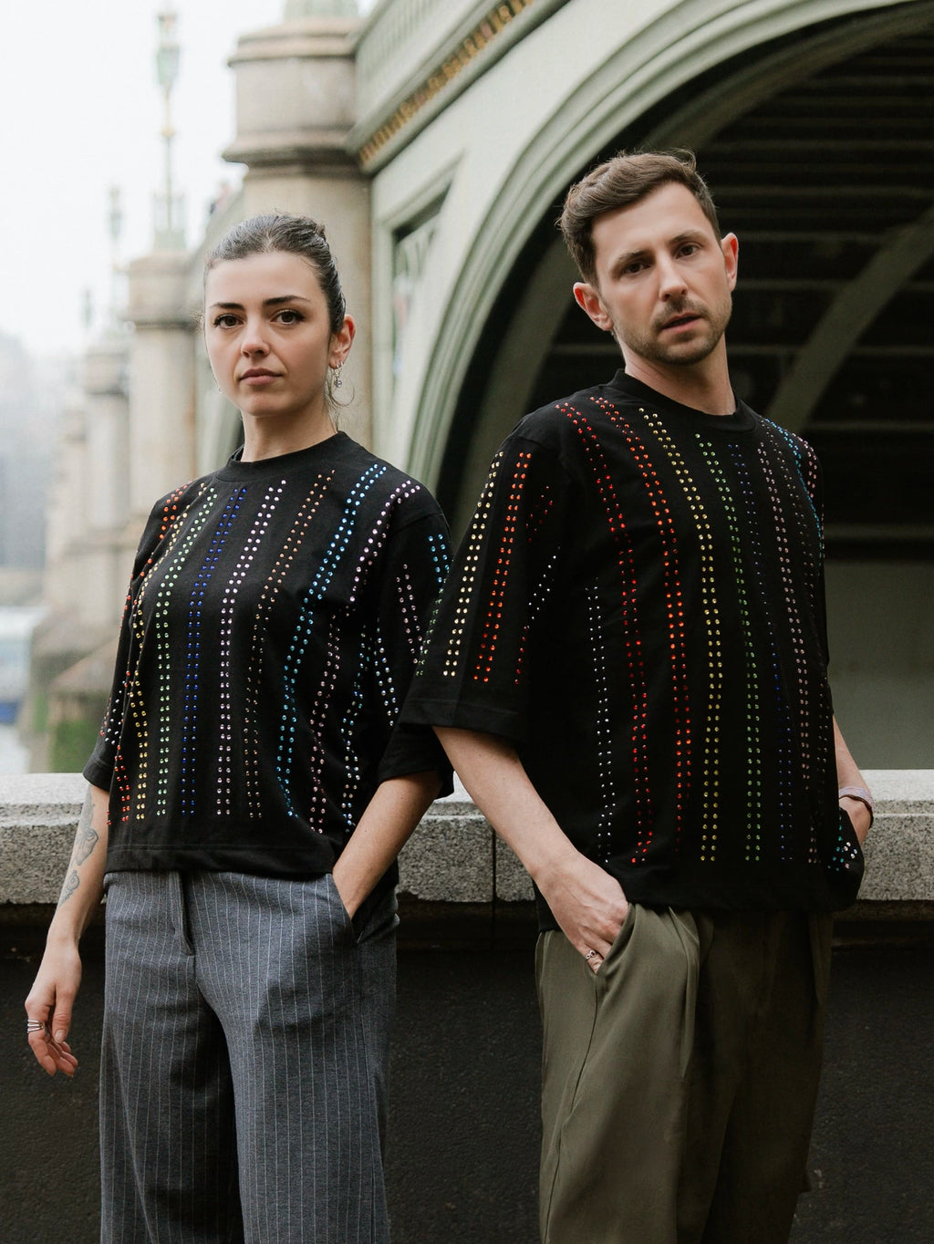 Two models wearing black Proud T-shirts with rainbow crystal lines , pride inspired, standing outdoors London Bridge Big ben London Iconic spot